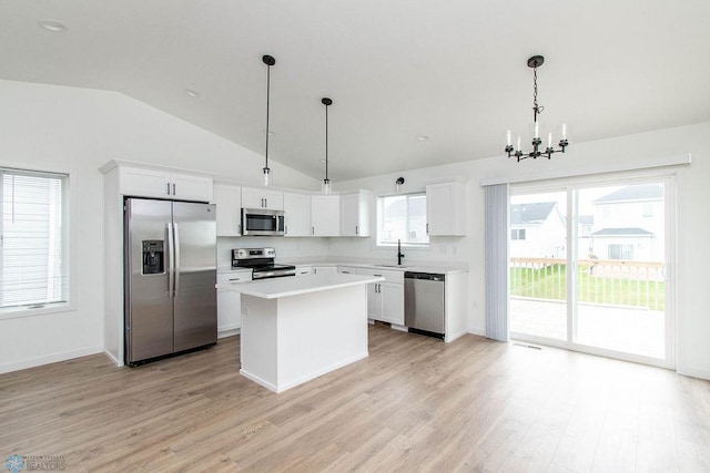 kitchen with a kitchen island, decorative light fixtures, stainless steel appliances, white cabinetry, and lofted ceiling