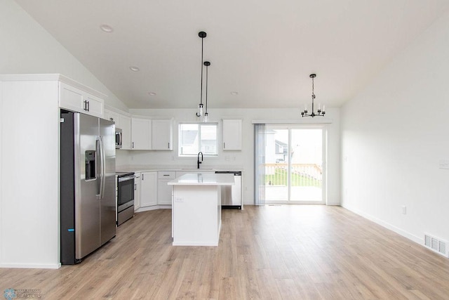 kitchen featuring a center island, hanging light fixtures, appliances with stainless steel finishes, lofted ceiling, and white cabinets