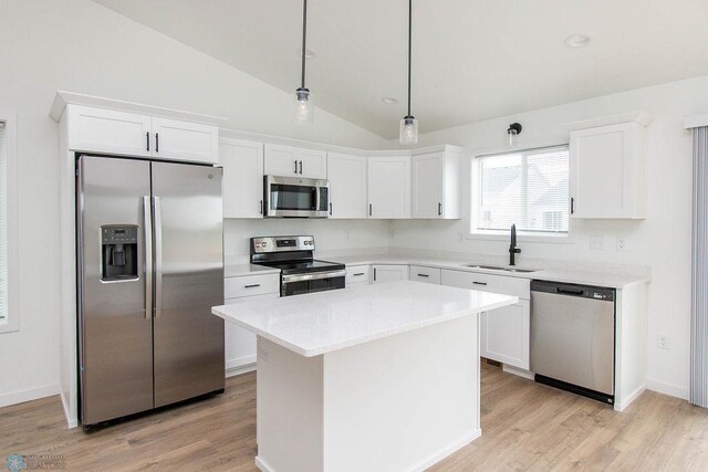 kitchen with a kitchen island, appliances with stainless steel finishes, sink, lofted ceiling, and white cabinets