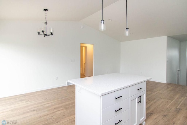 kitchen featuring vaulted ceiling, decorative light fixtures, light wood-type flooring, white cabinetry, and a kitchen island