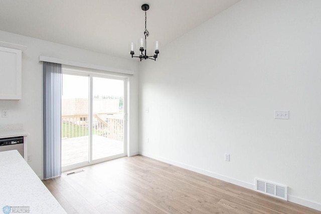 unfurnished dining area with light hardwood / wood-style floors, a notable chandelier, and vaulted ceiling