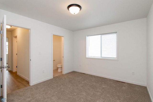 unfurnished bedroom featuring connected bathroom and light colored carpet