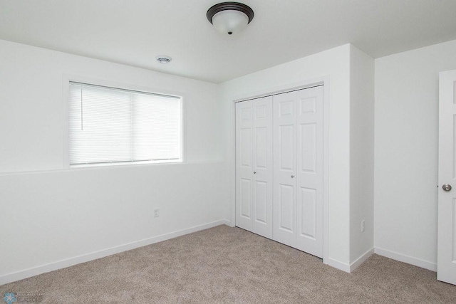 unfurnished bedroom featuring light colored carpet and a closet