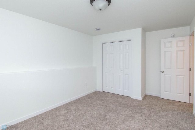 unfurnished bedroom featuring a closet and light colored carpet