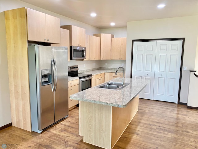 kitchen with light hardwood / wood-style flooring, light brown cabinetry, an island with sink, stainless steel appliances, and sink