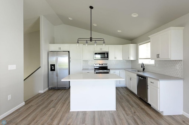 kitchen featuring stainless steel appliances, a center island, decorative backsplash, vaulted ceiling, and white cabinets