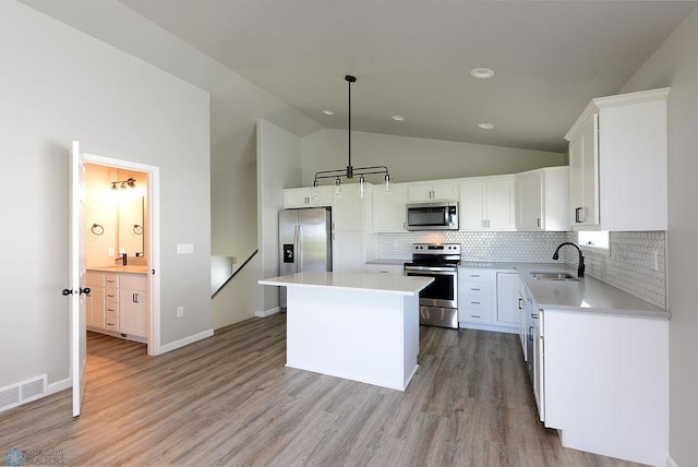 kitchen featuring stainless steel appliances, a kitchen island, sink, lofted ceiling, and white cabinets