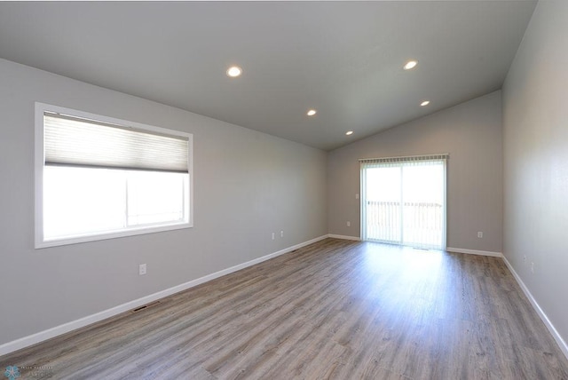 empty room featuring lofted ceiling and light hardwood / wood-style flooring