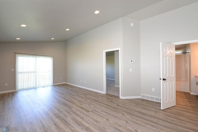 spare room with high vaulted ceiling and light hardwood / wood-style floors