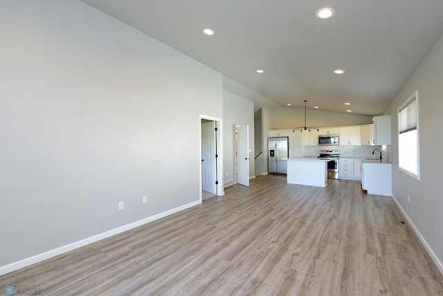 unfurnished living room featuring light hardwood / wood-style flooring, sink, and high vaulted ceiling