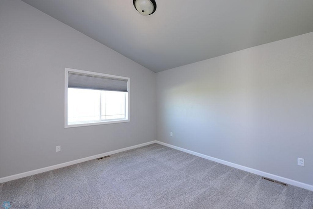 carpeted empty room with vaulted ceiling