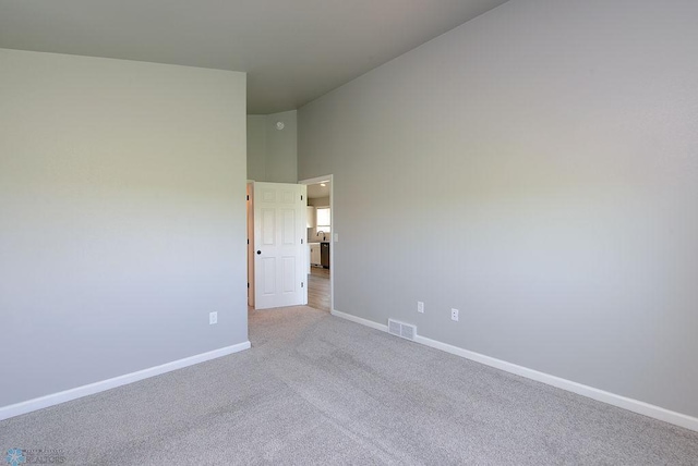 spare room with light colored carpet and high vaulted ceiling