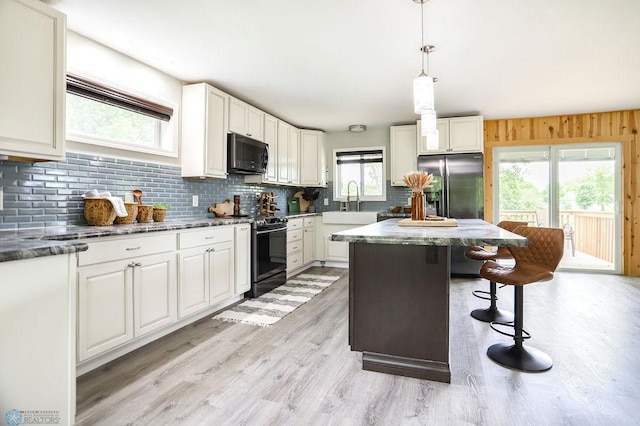 kitchen with appliances with stainless steel finishes, pendant lighting, a healthy amount of sunlight, and light wood-type flooring