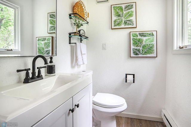 bathroom featuring wood-type flooring, vanity, baseboard heating, and toilet