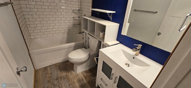 full bathroom with wood-type flooring, tiled shower / bath, vanity, and toilet