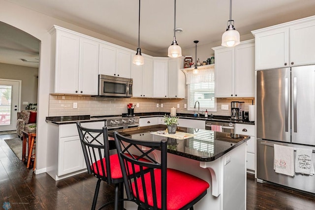 kitchen featuring a kitchen island, dark hardwood / wood-style floors, appliances with stainless steel finishes, a breakfast bar area, and white cabinets