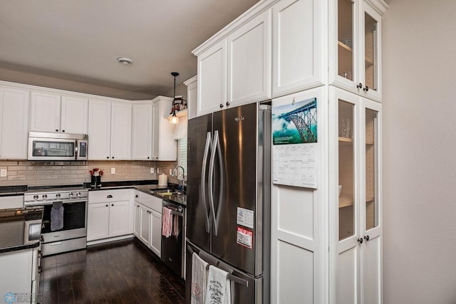 kitchen with dark hardwood / wood-style flooring, tasteful backsplash, hanging light fixtures, stainless steel appliances, and sink