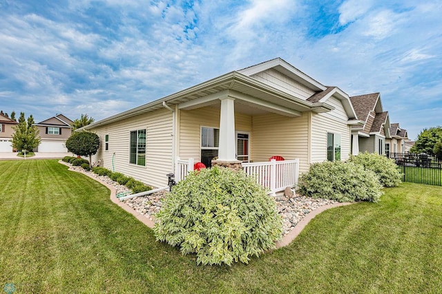 view of side of property featuring a yard, a garage, and covered porch