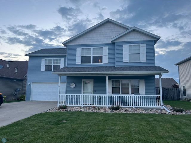 view of front of home featuring covered porch, a garage, and a front lawn