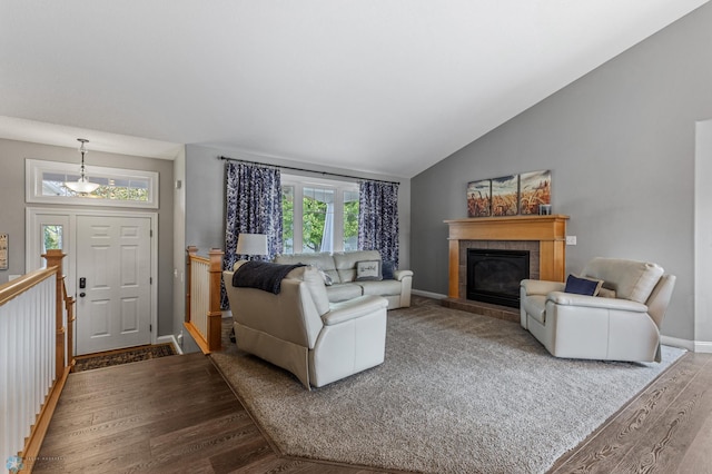 living room featuring vaulted ceiling, hardwood / wood-style flooring, and a tile fireplace