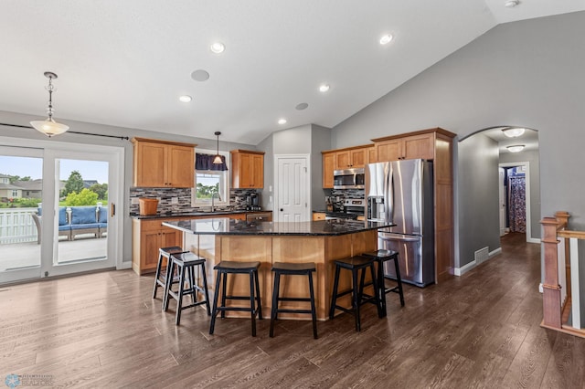 kitchen with decorative light fixtures, a kitchen island, stainless steel appliances, and dark hardwood / wood-style floors