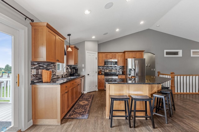 kitchen with dark hardwood / wood-style floors, decorative light fixtures, appliances with stainless steel finishes, a center island, and sink