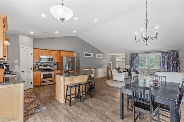 kitchen featuring a kitchen island, appliances with stainless steel finishes, sink, hardwood / wood-style flooring, and dark stone countertops