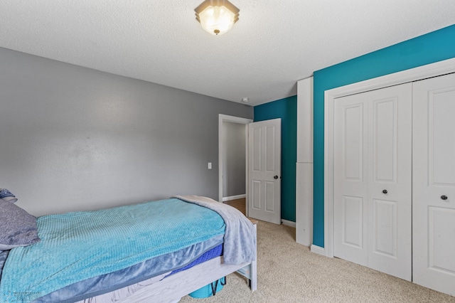 bedroom with a textured ceiling, a closet, and light carpet