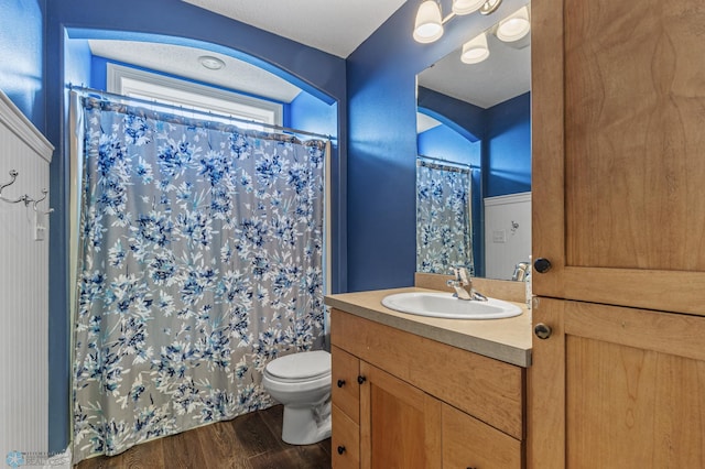 bathroom with toilet, vanity, hardwood / wood-style flooring, a textured ceiling, and a shower with shower curtain