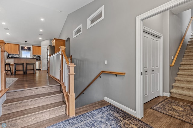 stairs with hardwood / wood-style floors and vaulted ceiling