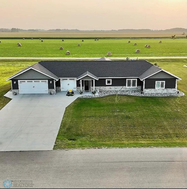 view of front of house featuring a garage, a front lawn, and a rural view