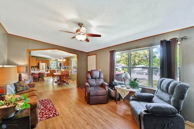 living room with light wood-type flooring, ceiling fan, plenty of natural light, and a textured ceiling