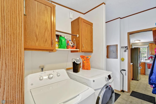 laundry area with a textured ceiling, washing machine and dryer, cabinets, and ornamental molding