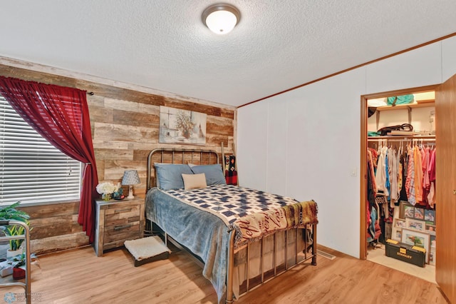 bedroom with a textured ceiling, wood walls, a closet, and wood-type flooring