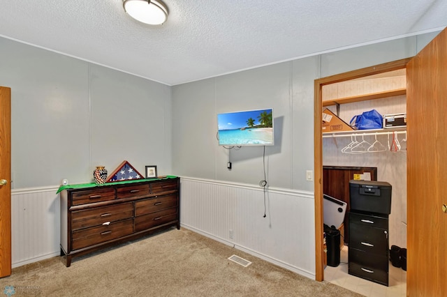 bedroom with a textured ceiling, light colored carpet, and wood walls