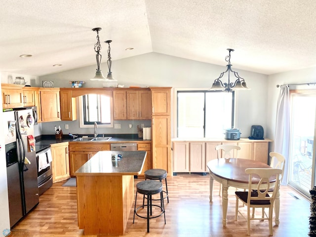 kitchen featuring light hardwood / wood-style flooring, vaulted ceiling, a center island, sink, and appliances with stainless steel finishes