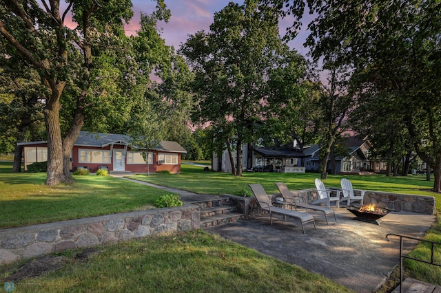 yard at dusk featuring an outdoor fire pit