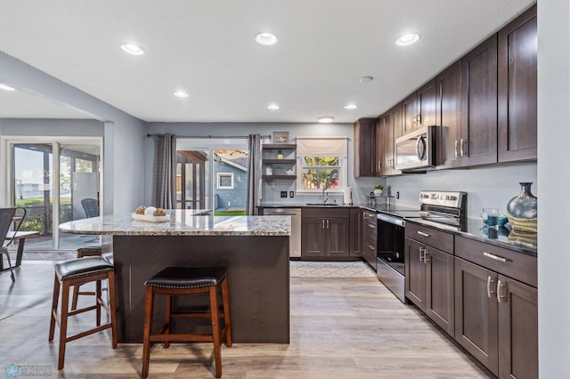 kitchen with appliances with stainless steel finishes, a breakfast bar area, stone countertops, and a healthy amount of sunlight