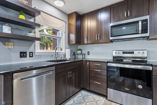 kitchen featuring dark stone countertops, appliances with stainless steel finishes, sink, and dark brown cabinetry