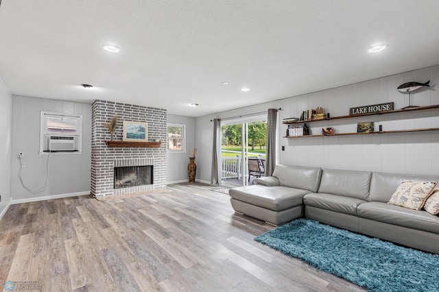 unfurnished living room with a textured ceiling, wood walls, a fireplace, cooling unit, and light wood-type flooring