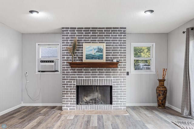 unfurnished living room with a fireplace, light wood-type flooring, a textured ceiling, and cooling unit