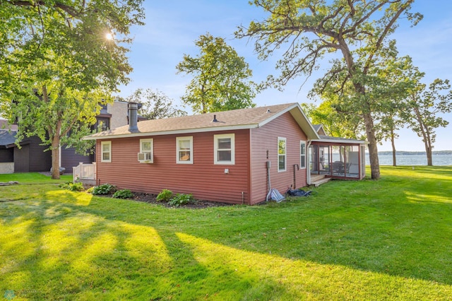 view of property exterior featuring a yard, cooling unit, a sunroom, and a water view