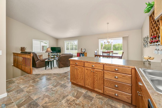 kitchen with sink, hanging light fixtures, an inviting chandelier, and vaulted ceiling