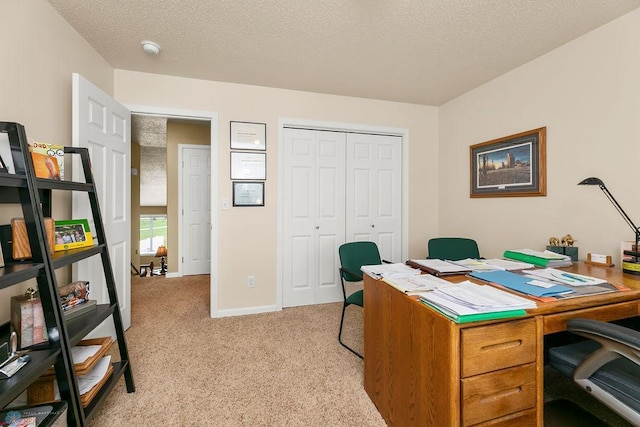 carpeted home office featuring a textured ceiling