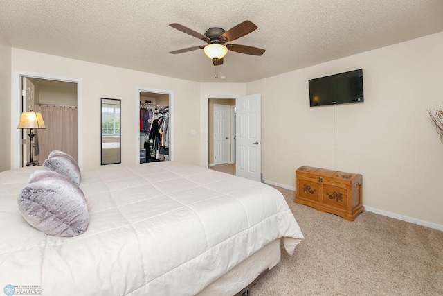 carpeted bedroom featuring a closet, ceiling fan, a spacious closet, and a textured ceiling