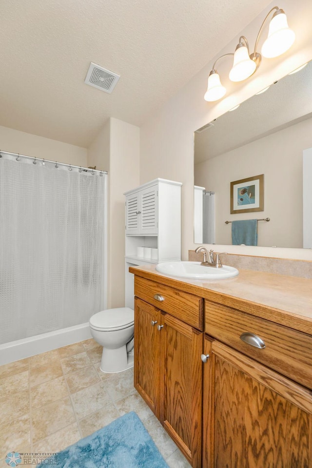 bathroom with a textured ceiling, vanity, toilet, and tile patterned floors