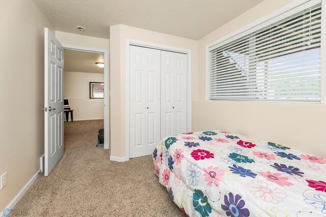 carpeted bedroom with a textured ceiling and a closet