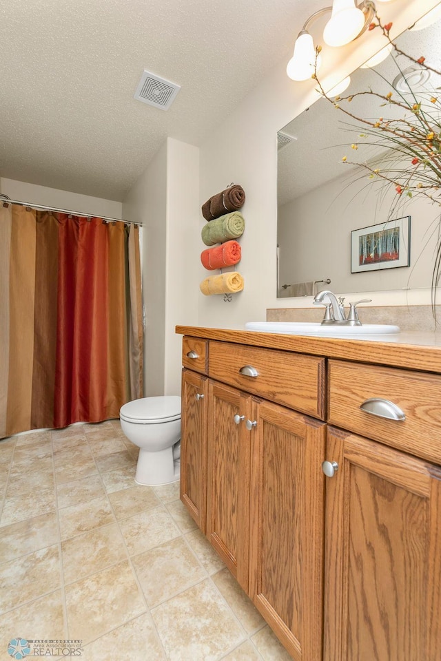 bathroom with vanity, toilet, tile patterned flooring, and a textured ceiling