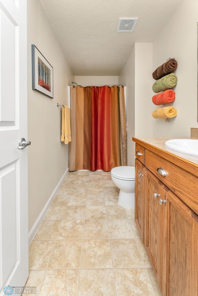 bathroom featuring toilet, tile patterned floors, vanity, a textured ceiling, and a shower with curtain