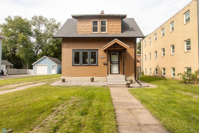 view of front of house featuring a garage, a front lawn, and an outbuilding